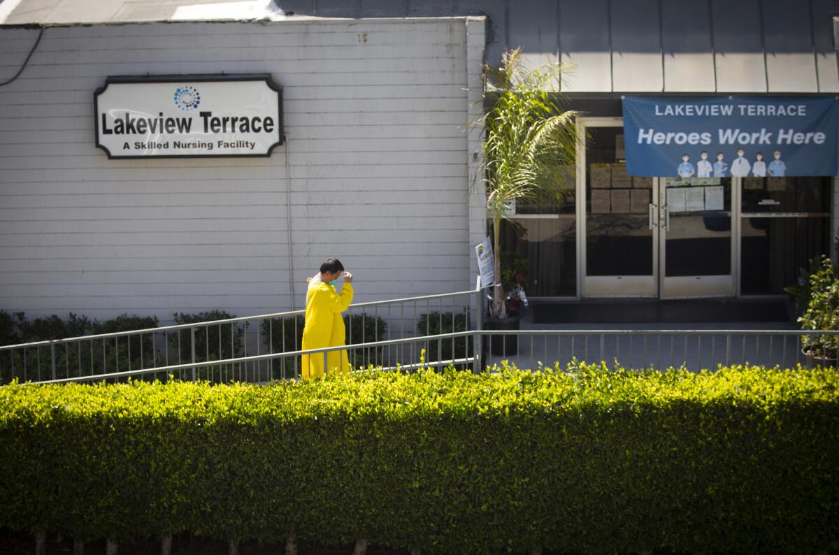 A man wearing an isolation gown walks toward the entrance of Lakeview Terrace nursing home.