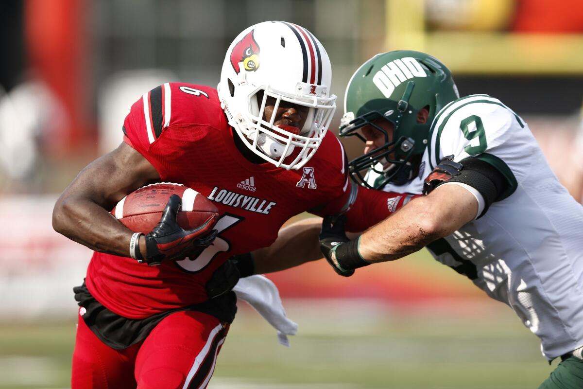 Louisville wide receiver Eli Rogers, left, breaks a tackle attempt by Ohio's Josh Kristoff during the Cardinals' 49-7 victory Sunday.