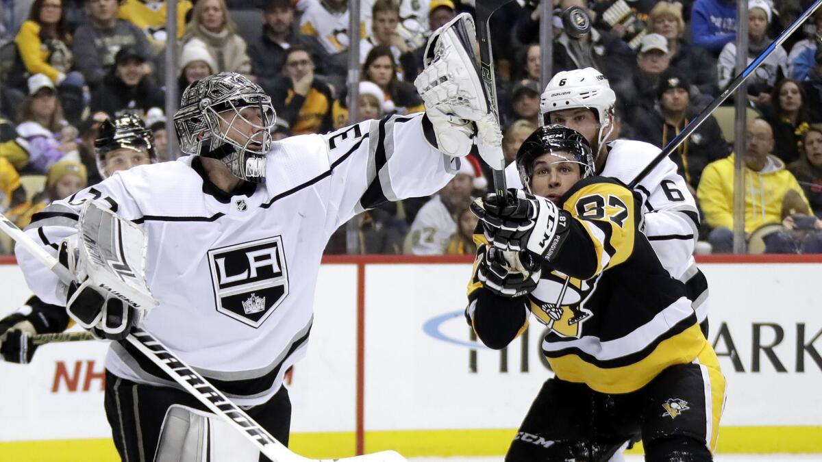 Kings goaltender Jonathan Quick (32) swats the puck out of the air before Pittsburgh Penguins' Sidney Crosby (87) can get his stick on it during the second period on Saturday in Pittsburgh.