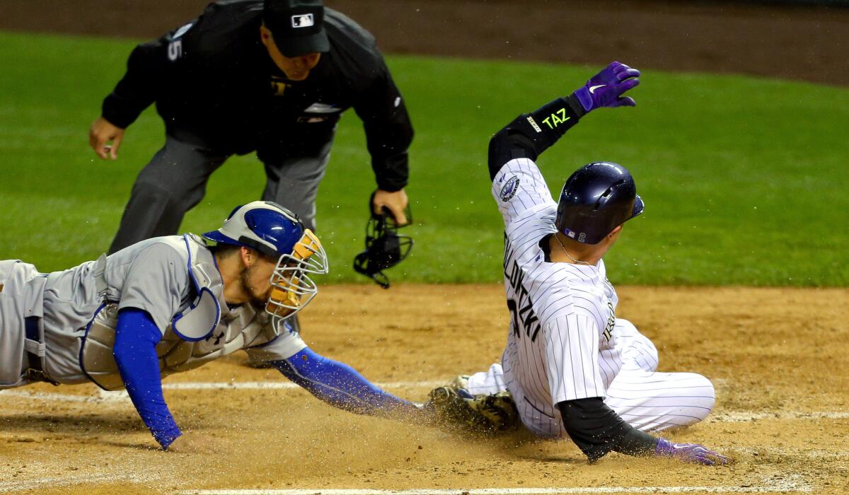 Dodgers catcher Yasmani Grandal tags out Rockies shortstop Troy Tulowitzki as umpire Tim Timmons gets a close look at the play in the fourth inning Friday night in Denver.