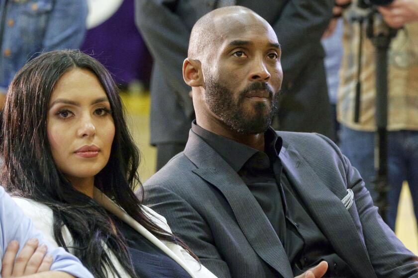 Kobe Bryant and his wife, Vanessa, watch as Rob Pelinka, right, speaks March 10, 2017. 