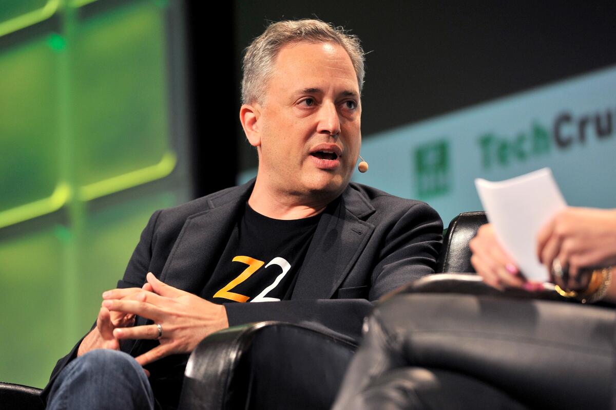 Venture capitalist David Sacks speaks while seated in a dark blazer, T-shirt and headset microphone