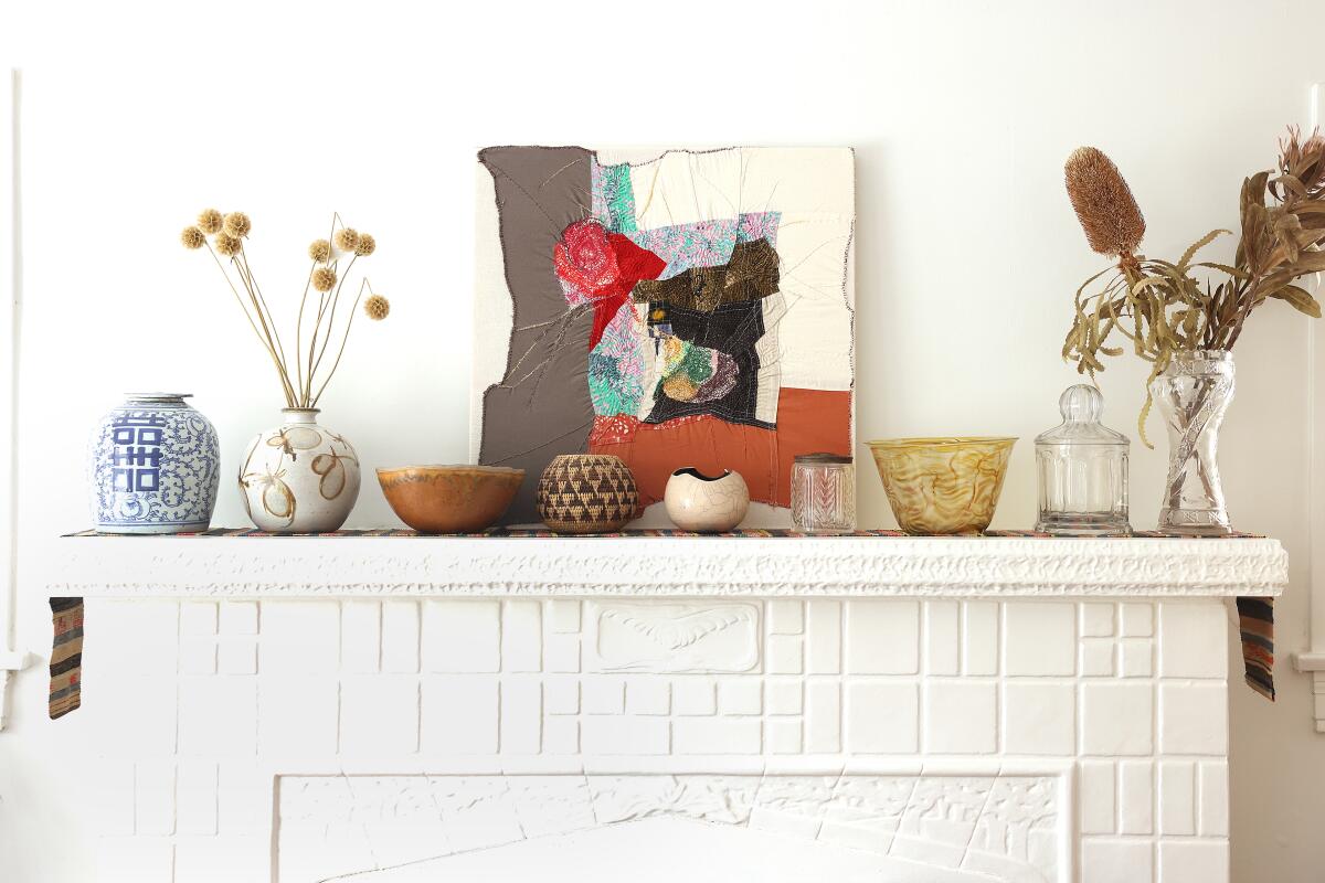 Ceramics, flowers and art rest on a white mantle