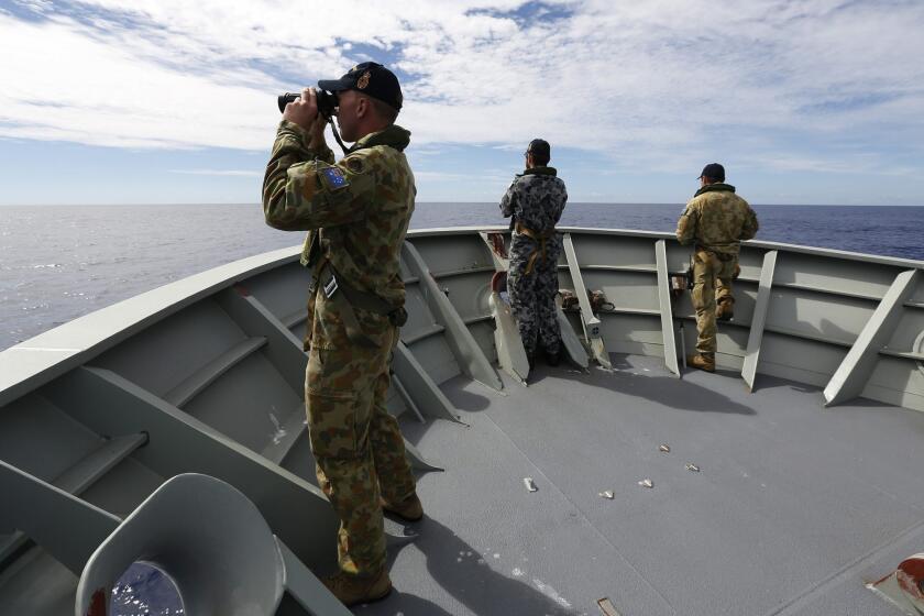 Australian Defense Force personnel aboard the Royal Australian Navy ship Perth search for debris from missing Malaysia Airlines Flight 370.