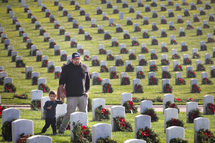 Ben Bramer of La Mesa shows his son, Mattis, 2, some of the headstones during the Wreaths Across America wreath laying event at Fort Rosecrans National Cemetery, December 14, 2019 in San Diego, California to honor veterans. Between 6,000 and 7,000 wreaths were placed at the headstones in Ft. Rosecrans, one of more than 1,600 locations throughout America, at sea and abroad receiving the wreaths during the event.