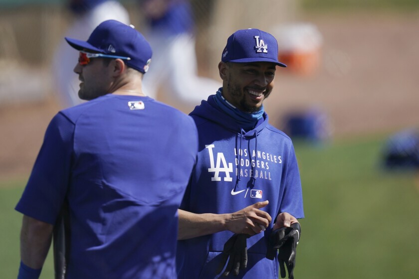 Dodgers right fielder Mookie Betts, right, smiles while talking with A.J. Pollock during spring training.