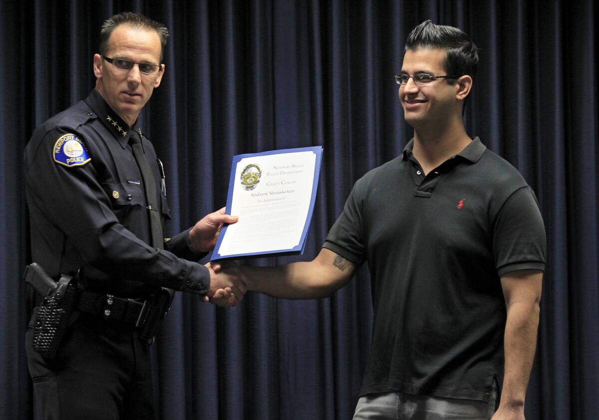 Newport Beach police chief Jay Johnson, left, hands Andrew Shoashekan a chief's citation during a ceremony at the Newport Beach Police Department on Thursday. Shoashekan was acknowledged for stopping a suicidal woman from jumping off an 18th floor balcony at Island Hotel in Newport Beach.