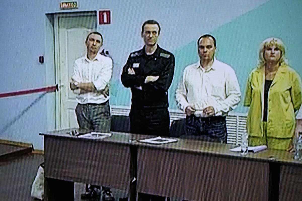 Russian opposition leader Alexei Navalny is seen on a TV screen standing among his lawyers.