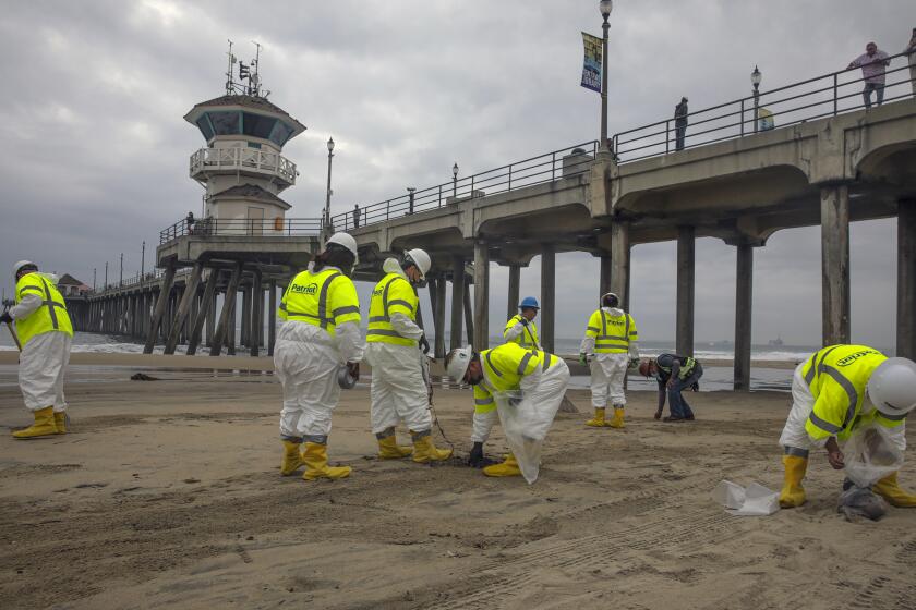 Huntington Beach, CA - October 07: An army workers comb they beach to remove any remnants of oil spill washed ashore on the beach on Thursday, Oct. 7, 2021 in Huntington Beach, CA. (Irfan Khan / Los Angeles Times)