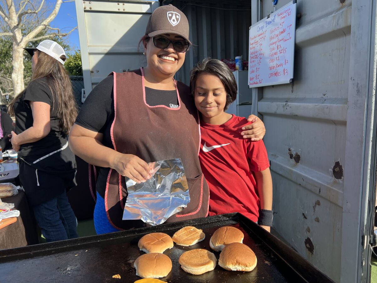 Rocio Velazquez, the mother of Crespi sophomore Diego Velazquez, works at the snack bar with younger son David at her side.