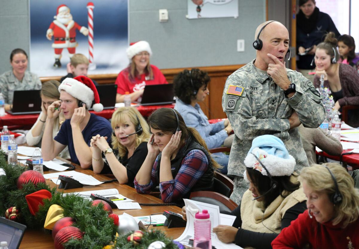 U.S. Northern Command Chief of Staff Maj. Gen. Charles D. Luckey and volunteers take phone calls from children around the world. A misprint in a newspaper advertisement kicked off NORAD's Santa-tracking activities 60 years ago.