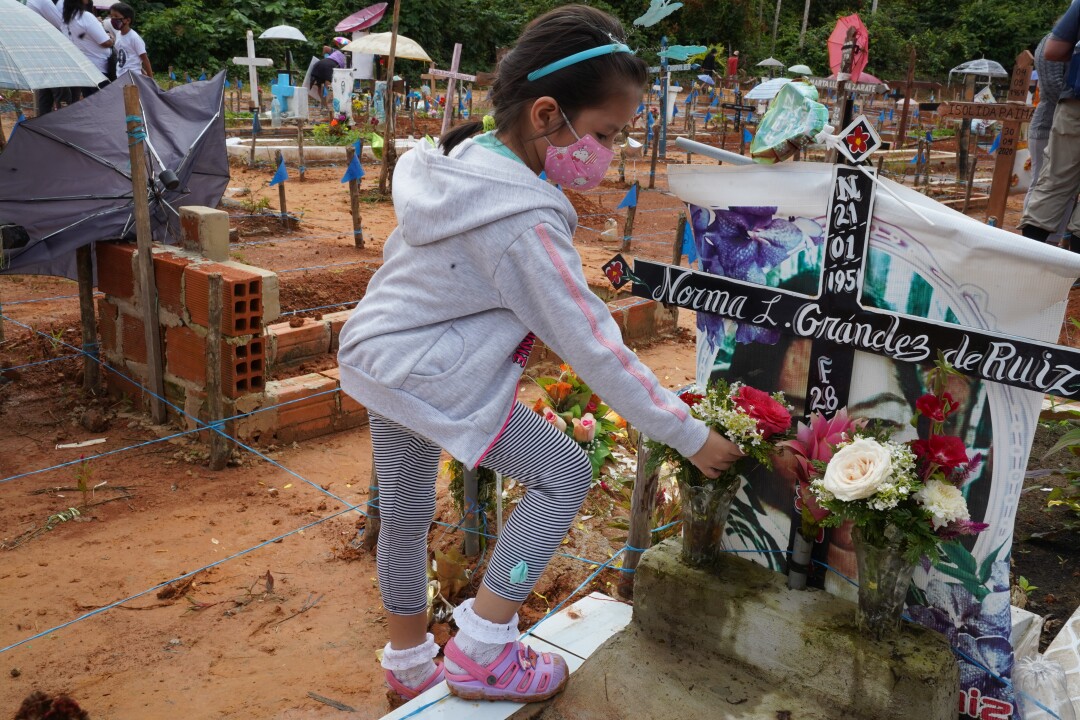 Jade Jesabed, 6, places flowers for her grandmother at a makeshift cemetery outside Iquitos, Peru.