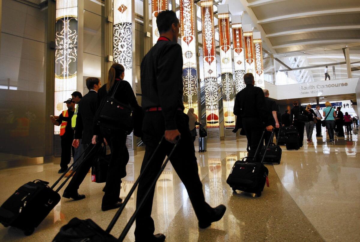 Passengers roll carry-ons through Tom Bradley International Terminal at LAX. A study found that a lot of boarding time is wasted as passengers look for space in overhead compartments to stow their carry-on bags.