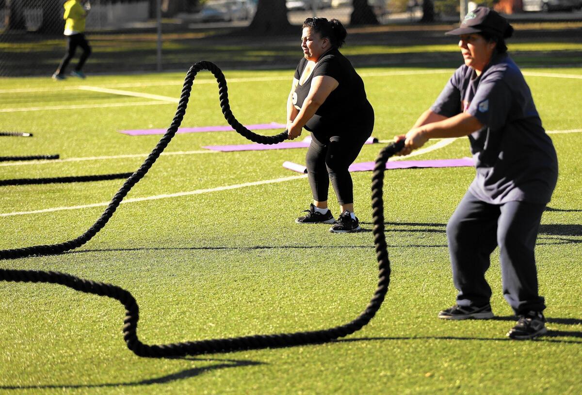 Guadalupe Arenales, left, and Maria Rivera maneuver 50-foot battle ropes during an exercise class led by Cal State Northridge kinesiology students at Lanark Park in Canoga Park.