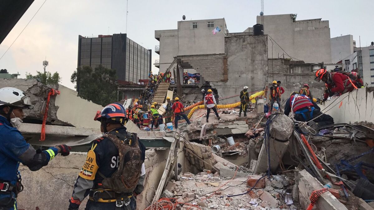 Emergency workers continue the recovery effort from the roof of the office building at Avenida Alvaro Obregon 286. (Rong-Gong Lin II / Los Angeles Times)