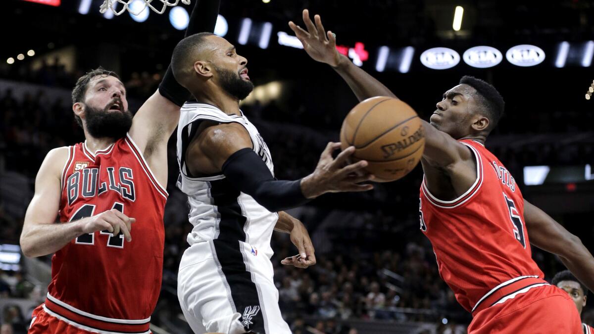 Spurs guard Patty Mills, center, passes the ball as he is pressured by Bulls forwards Nikola Mirotic (44) and Bobby Portis (5) during the second half Thursday night.