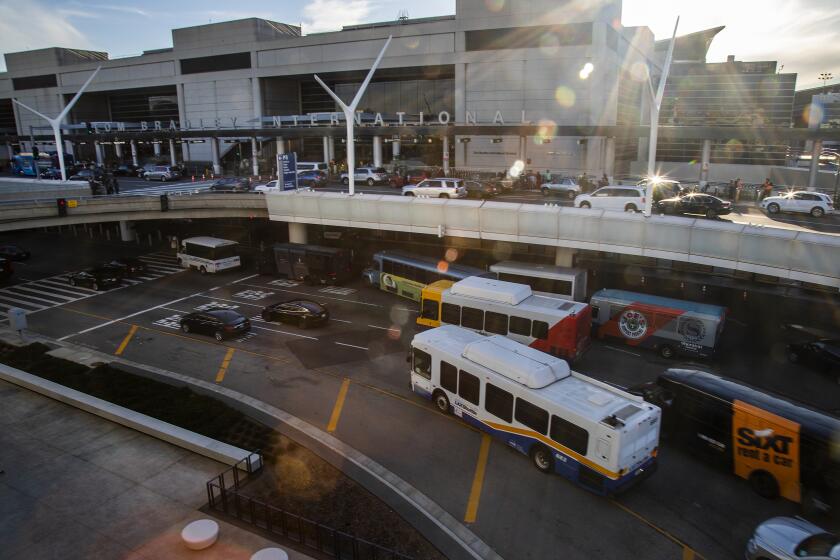 LOS ANGELES, CA - MARCH 14, 2019: Travelers are dropped off at the top departure level at the International terminal as shuttle buses maneuver to pick-up spots on the lower arrivals level at LAX on March 14, 2019 in Los Angeles, California. A new Automated People Mover train is under construction and will reduce traffic by 3,000 vehicles per day.(Gina Ferazzi/Los AngelesTimes)