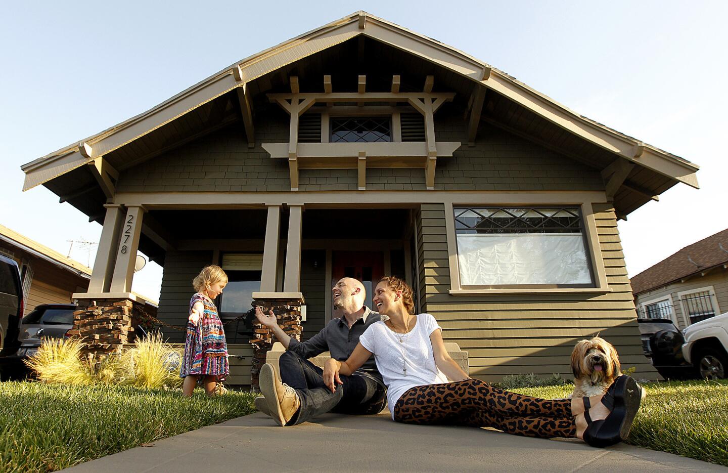 Mark and Jillian Dillon and their 1-year-old daughter, Staley Rae, and dog Guv'nor hang out in front of their home in Jefferson Park. The Dillons, who had been renting in Venice, purchased the rehabbed Craftsman home a year ago.