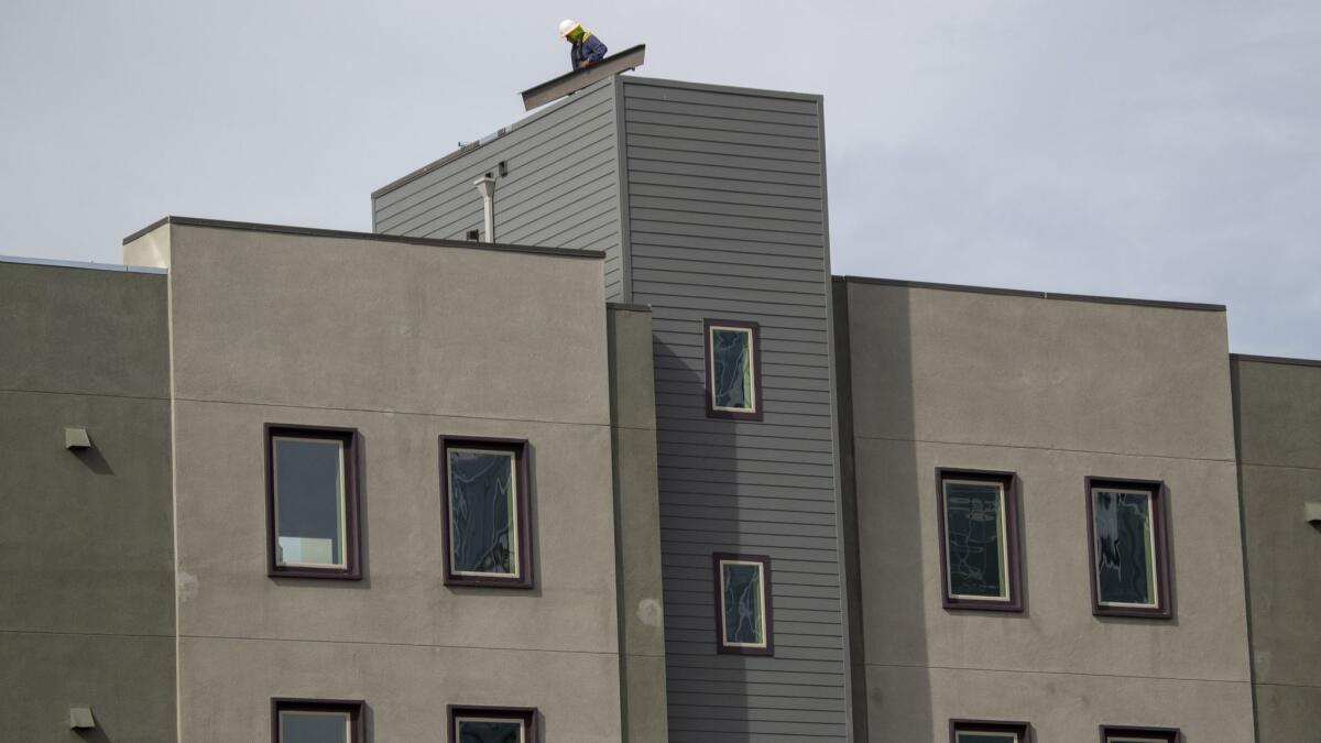 A construction crew works on Central Park West homes and apartments in Irvine. A report says Irvine is on pace to meet its low-income housing target sometime after the year 3000.