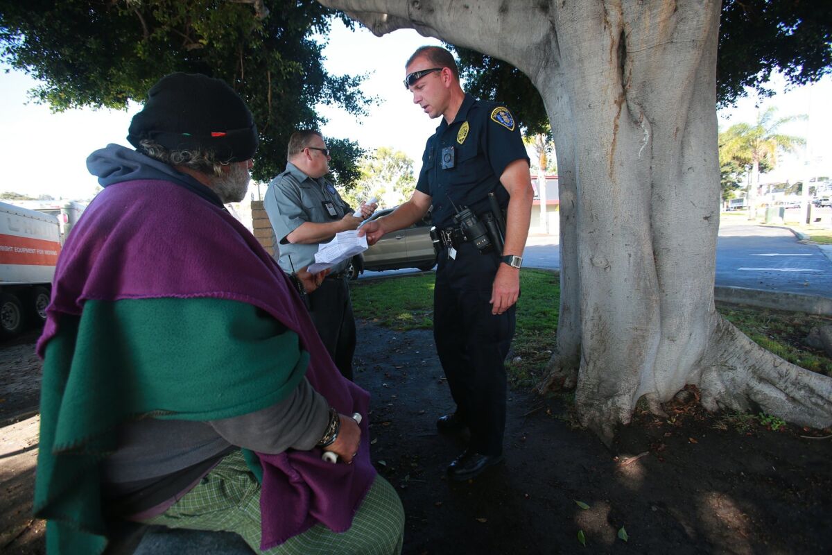 HOT team officer Brian Lucchesi and PERT clinician Greg Whiteford, left, talk with people in the Midway area about the assaults on homeless people.