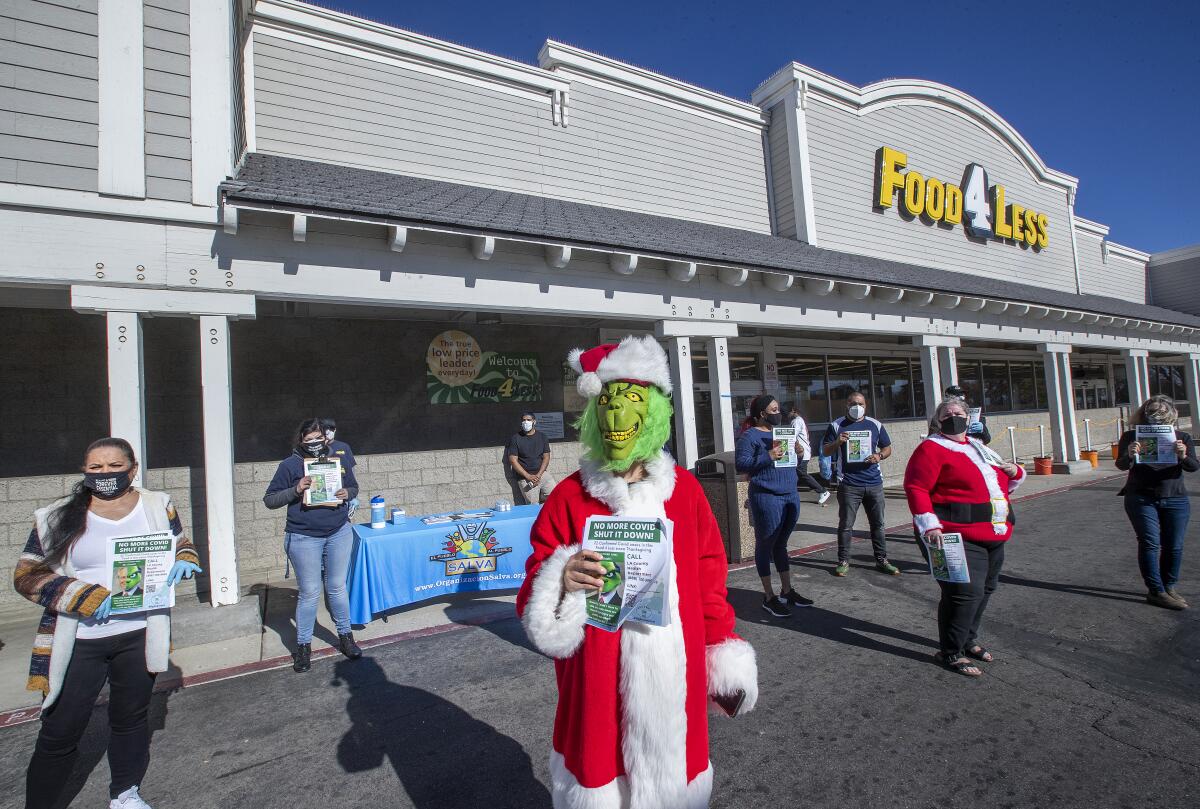 People protesting outside a supermarket, including someone dressed as the Grinch