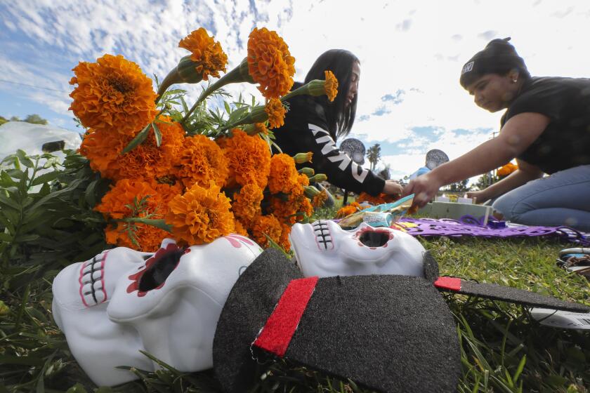 Maria Duran, left, and daughter Angelica Jacquez, 17, decorate the graves of Duran's parents, Juan and Maria Duran, with marigold flowers during the Dia de los Muertos celebration at Eternal Hills Memorial Park on Saturday, November 2, 2019 in Oceanside, California.