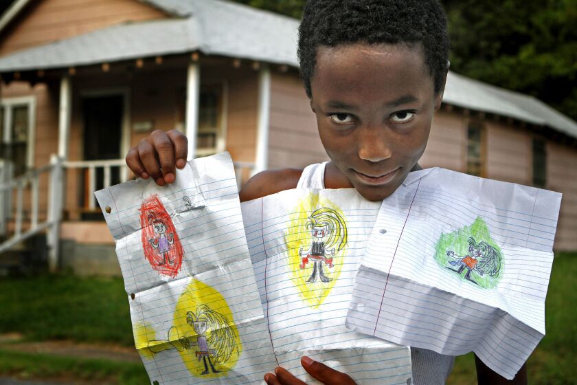 Demarius Cummings shows his cartoon drawings that he usually keeps folded up in his pockets. He and his sister lived in a foster home while his mother worked through lifestyle problems. The children were recently reunited with their mother and the family receives financial aid and counseling from the agency.