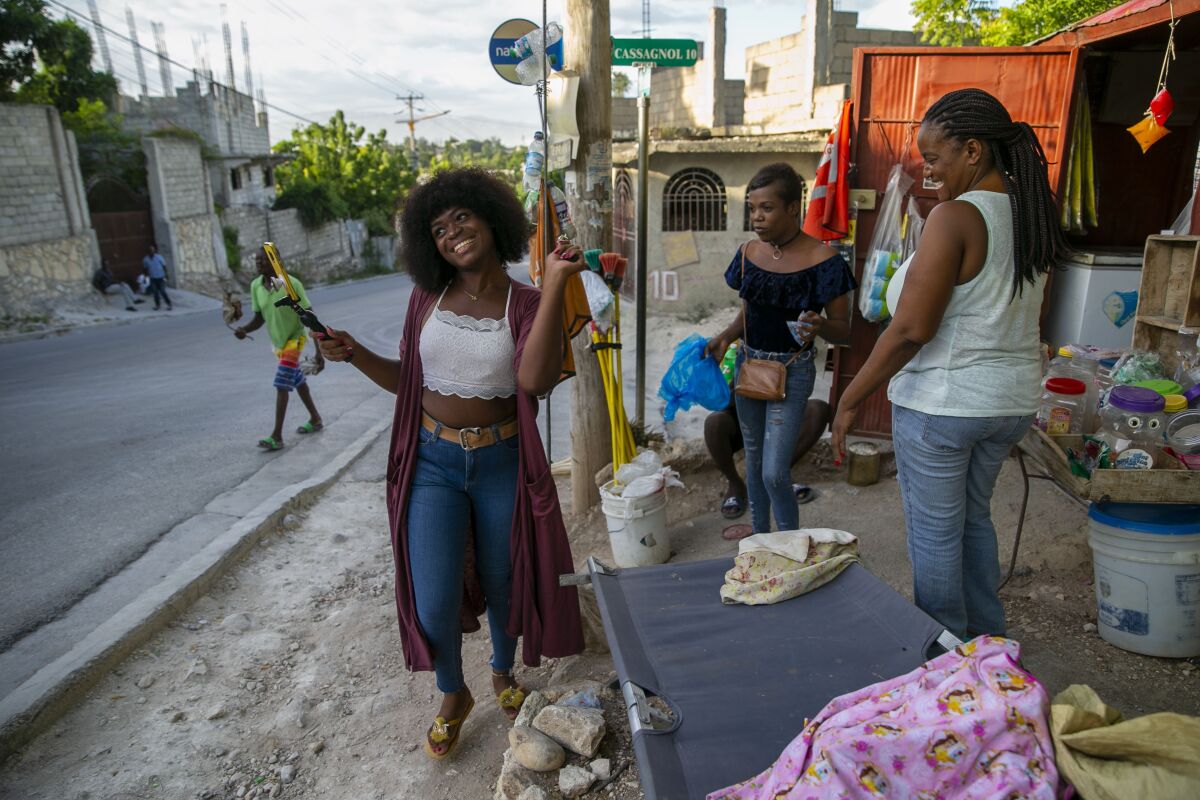 Transgender Semi Kaefra Alisha Fermond smiles after receiving a lollipop from neighborhood street vendors as she makes her way to the Kay Trans Haiti center to celebrate her 24th birthday, in Port-au-Prince, Haiti, Friday, Aug. 7, 2020. Prejudice and discrimination against transgender people is common in Haiti, but the Kay Trans Haiti center is providing a haven where transgender people can feel welcome and accepted. (AP Photo/Dieu Nalio Chery)