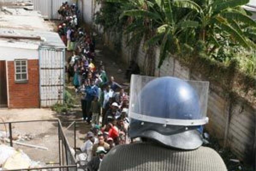 NOT ENOUGH: A police officer watches over people waiting in line for sugar in Harare. Shortages have made long lines the way of life. Many in queues are hungry, tired, desperate to get food for their family, and spend all their days waiting