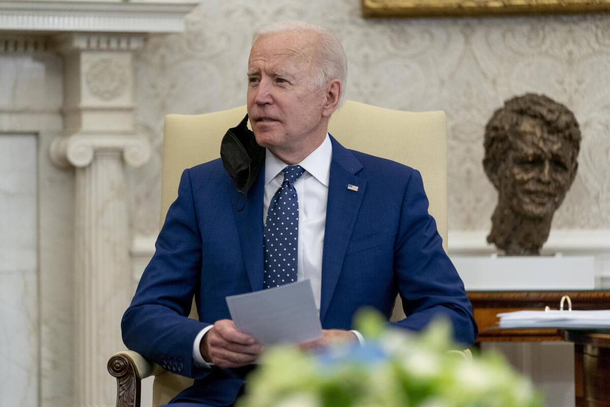 President Biden holds a paper in his hands while sitting in the White House