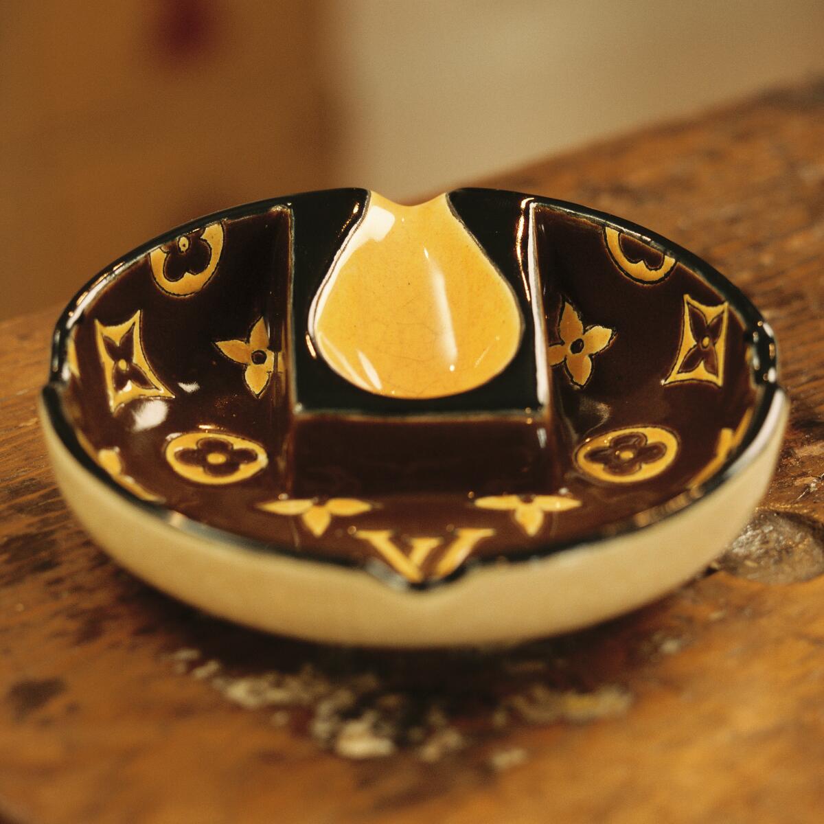 A bowl-shaped ashtray with the Louis Vuitton logo.