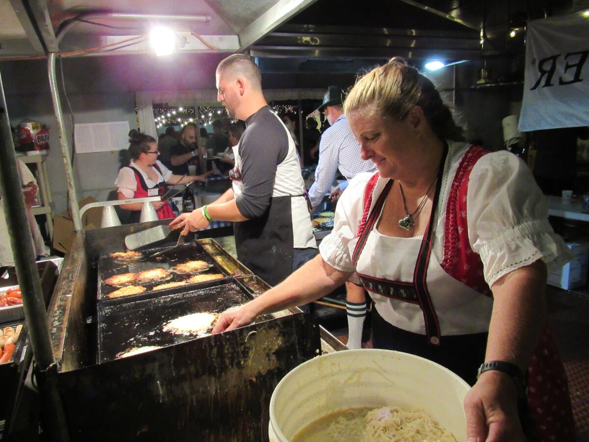 Claudia Jensen of the German-American Societies of San Diego (right) puts potato pancake batter on a grill.