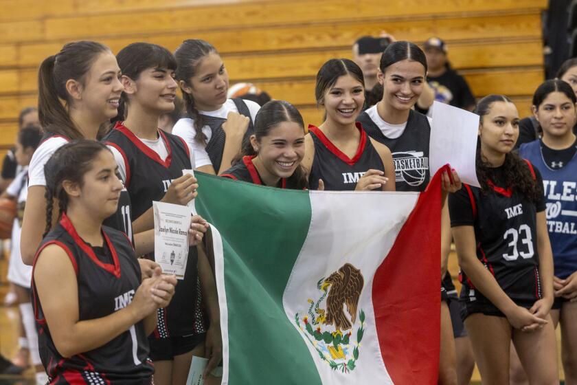 Members of Lady IME hold the Mexican flag during a game at the opening ceremony of Copa Oaxaca, Mexican basketball national team trials at Cabrillo High School in Long Beach, Calif. on August. 24, 2024