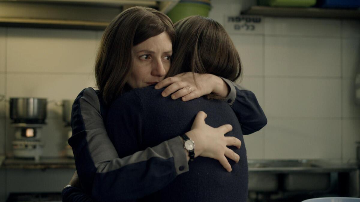 Two women embrace in a kitchen