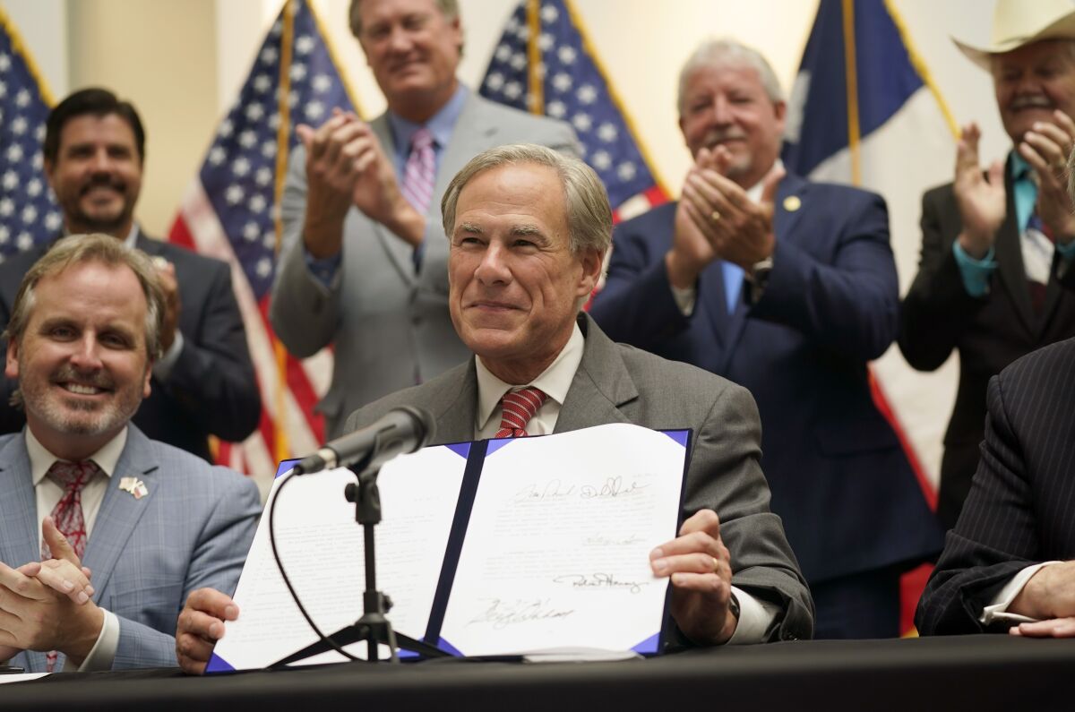 Texas Gov. Greg Abbott shows off Senate Bill 1, which further tightens Texas’ strict voting laws.