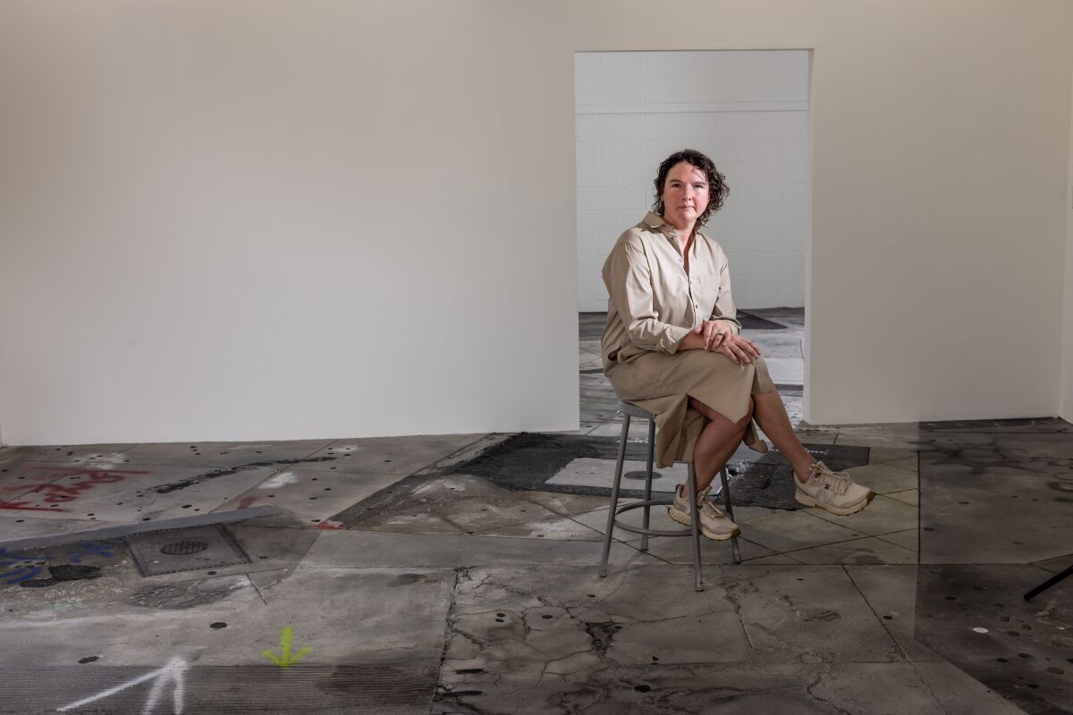 A woman sits on a metal stool in her art studio.