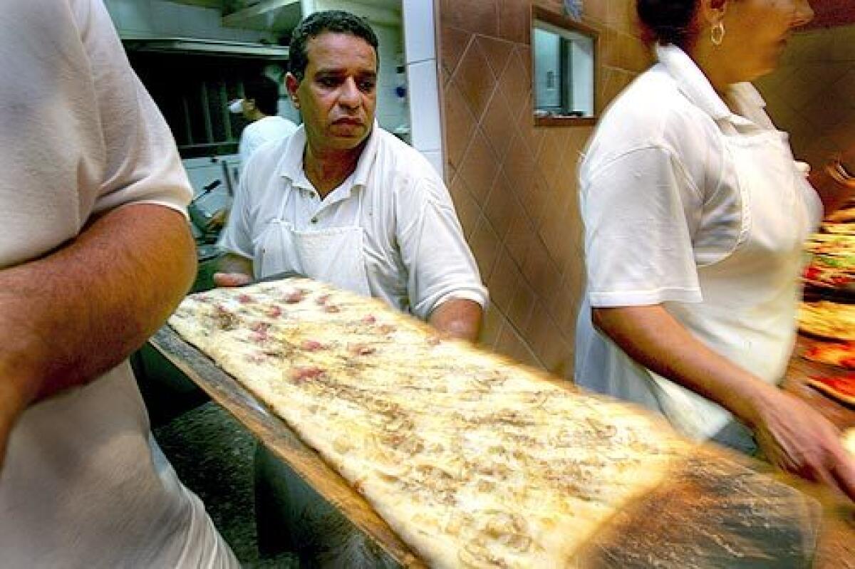WHEN IN ROME: Magdy el Shahidy readies pizza at the restaurant. His family has made a point of assimilating.
