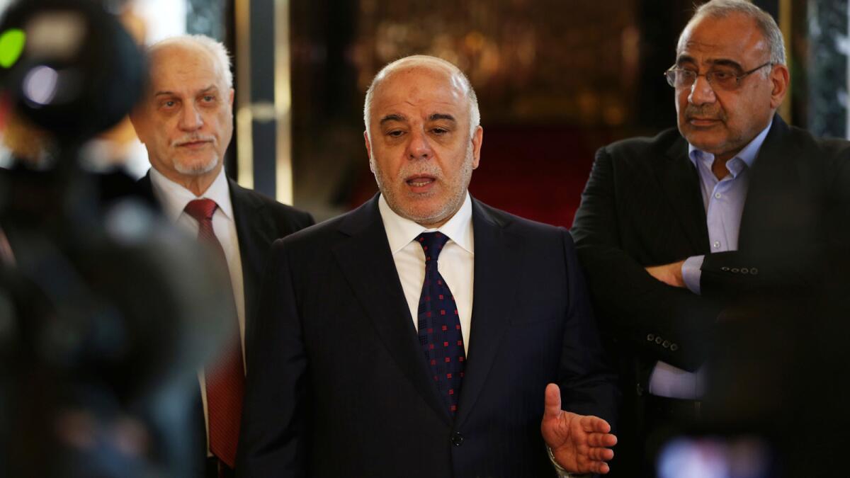 Iraqi Prime Minister Haider Abadi, center, holds a news conference at Baghdad's airport before leaving for the United States.