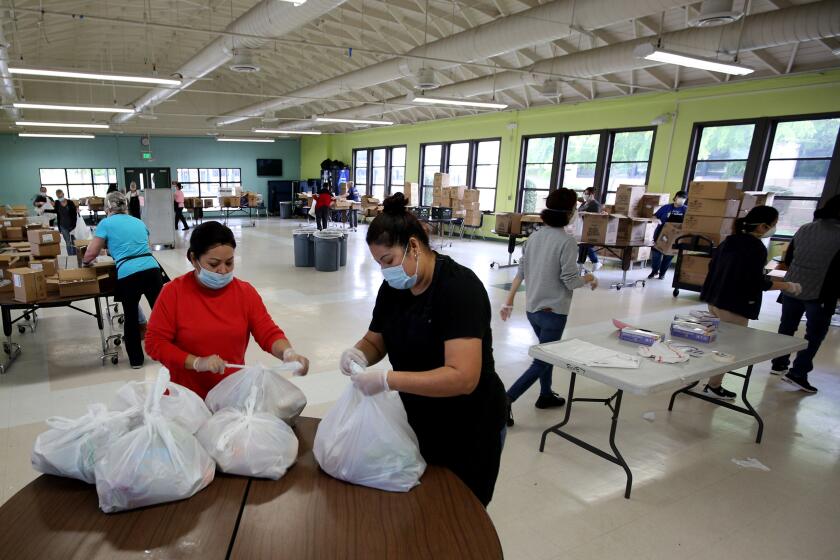 Burbank Unified cafeteria workers prepare five-day meal packages for students across the district, at Burbank Middle School on Tuesday. March 24, 2020.