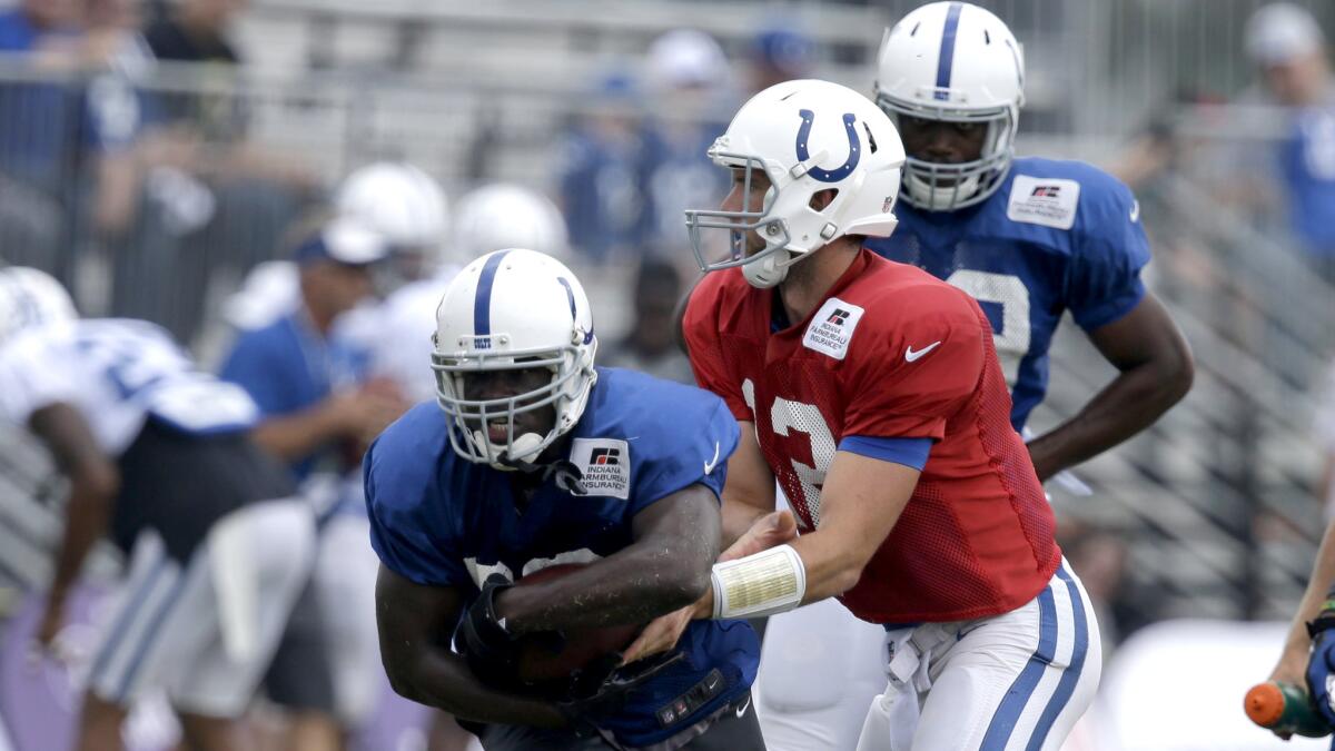 Colts quarterback Andrew Luck (12) hands off to running back Frank Gore during a drill at training camp on Aug. 10.