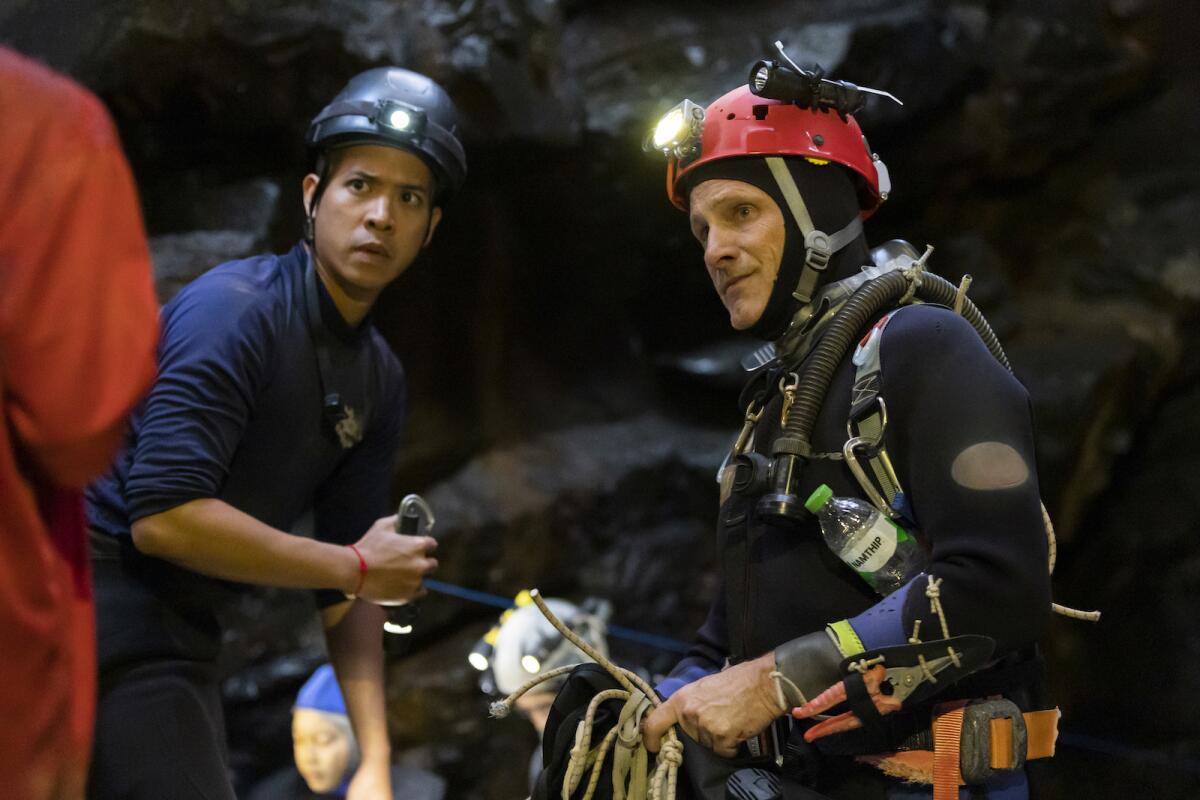 Two rescue divers with lights on their helmets in the movie "Thirteen Lives."