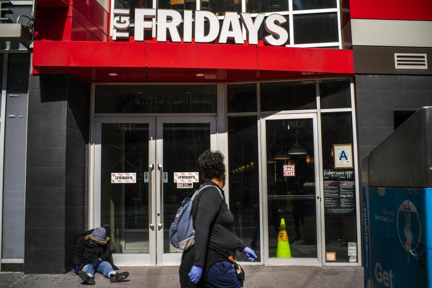 NEW YORK, NY - MARCH 24: A homeless person rests on a street as a person walks by a TGI Fridays while the streets are empty due to the coronavirus on March 24, 2020 in Queens, New York City. New York City has about a third of the nations confirmed coronavirus (COVID-19) cases, making it the epicenter of the outbreak in the United States. (Photo by Eduardo Munoz Alvarez/Getty Images)