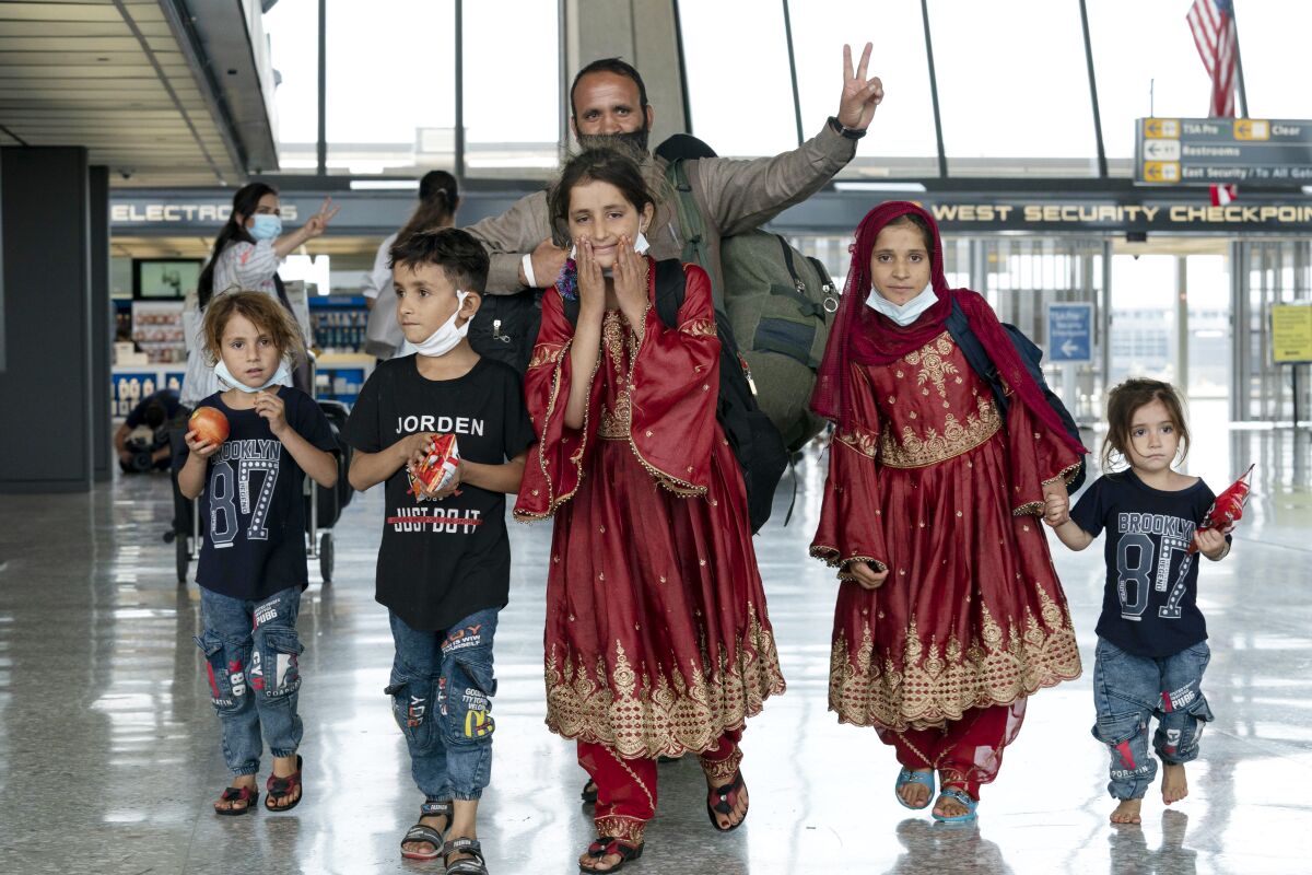 Families evacuated from Kabul, Afghanistan, walk through Washington Dulles International Airport.