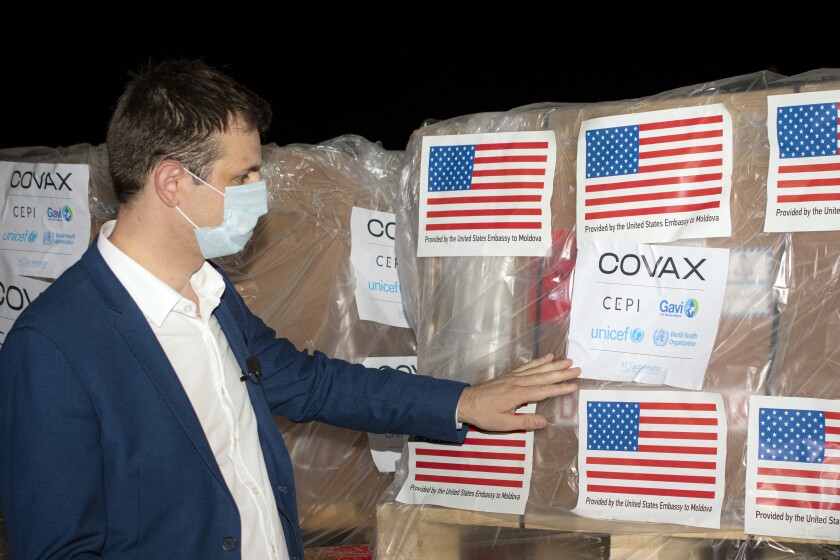 Veaceslav Gutu from the National Agency for Public Health adjusts a sticker that reads "Covax" on boxes containing COVID-19 vaccines, at the Chisinau International Airport, in Chisinau, Moldova, Monday, July 12, 2021.The first 150,000 doses of a 500,000-strong batch of Johnson & Johnson vaccines arrived in Moldova's capital Monday as part of a donation from the United States that will help the former Soviet republic tackle the coronavirus pandemic.(AP Photo/Nadejda Roscovanu)
