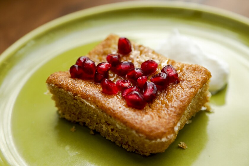 Walnut cake in olive oil garnished with pomegranate seeds.