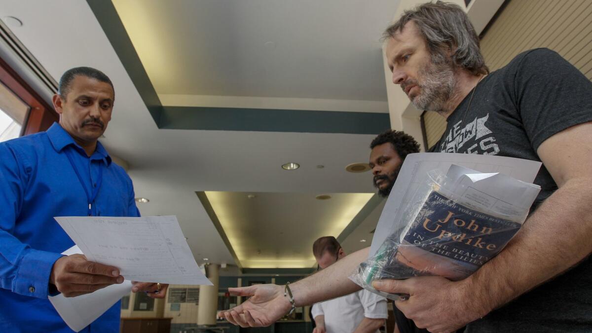 Victor Key, case manager for Project 180, left with Ellis Pickering, right and Aaron Float, center who are being released at Los Angeles County Jail, as a condition of probation they are entering an interim housing program designed to lead to permanent housing.