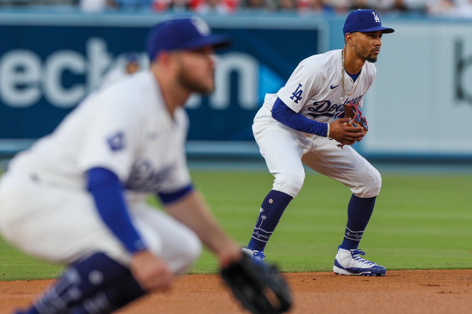 Dodgers shortstop Mookie Betts and third baseman Max Muncy crouch and lean forward before a pitch during a game.