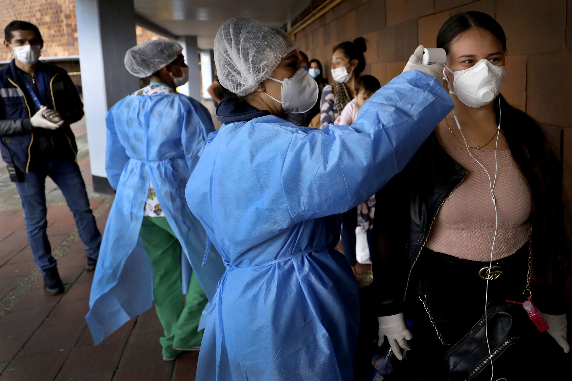 COLOMBIA: A nurse takes the temperature of a woman outside the main bus terminal in Bogota on March 24.