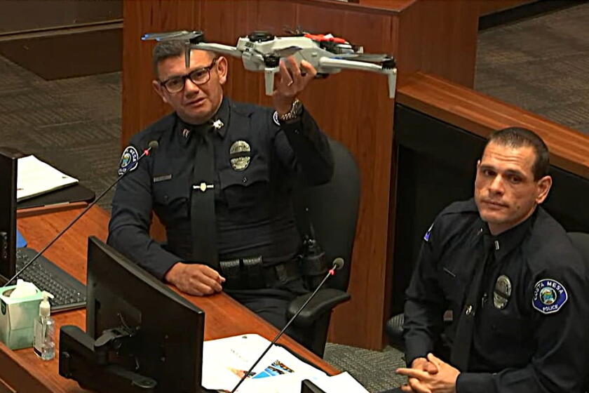 CMPD Capt. Carlos Diaz, left, holds up a Skydio X-10 drone during a Costa Mesa City Council meeting Tuesday.