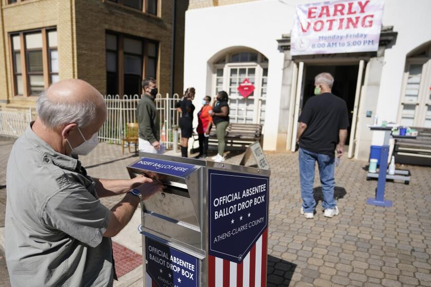 A voter drops their ballot off during early voting, Monday, Oct. 19, 2020, in Athens, Ga. With record turnout expected for this year's presidential election and fears about exposure to the coronavirus, election officials and advocacy groups have been encouraging people to vote early, either in person or by absentee ballot. (AP Photo/John Bazemore)